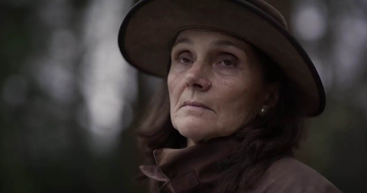 Charlotte in a wide-brimmed hat in the woods, from her memory film